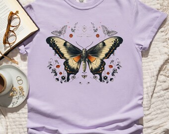 May include: A lavender t-shirt with a graphic print of a large butterfly with orange and black wings surrounded by small flowers and butterflies. The text "COMMON THREADS" is printed on the tag.