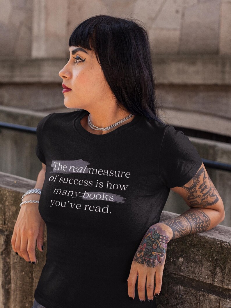 May include: A black t-shirt with a white graphic that reads "The real measure of success is how many books you've read."