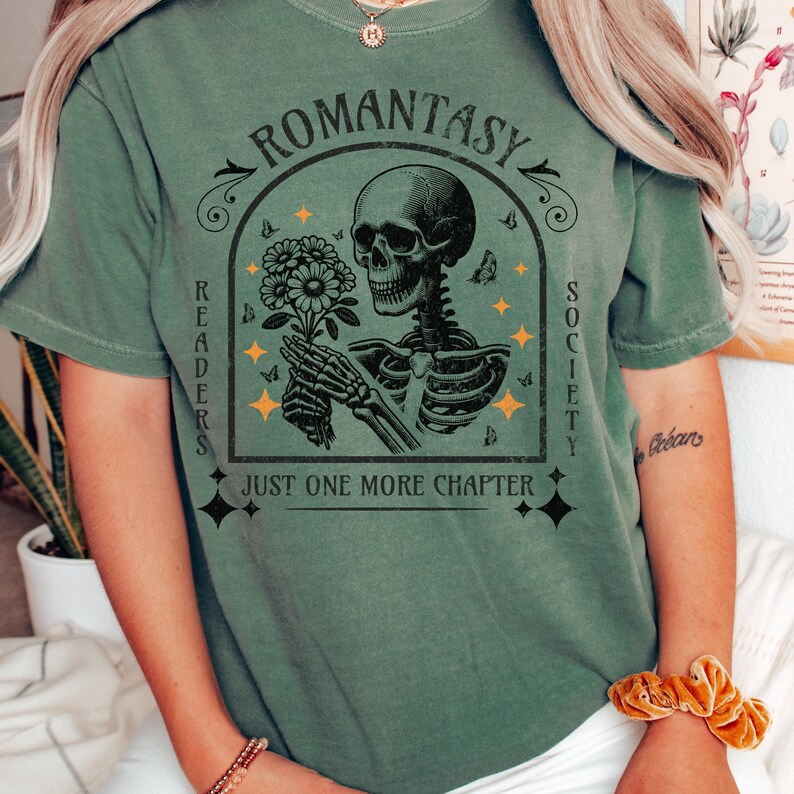May include: Green t-shirt with a skeleton holding flowers and the text "Romanstasy Readers Society Just One More Chapter".