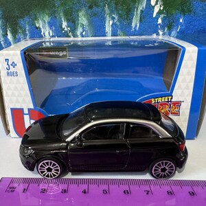 Peut inclure: Une voiture miniature noire avec des garnitures argent&eacute;es, pr&eacute;sent&eacute;e dans son emballage d'origine. La voiture jouet a des roues d&eacute;taill&eacute;es et un design &eacute;l&eacute;gant. L'emballage comprend le texte "STREET FIRE" et "3+ AGES". Une r&egrave;gle est au premier plan.