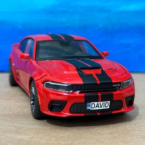 Könnte beinhalten: Roter Dodge Charger mit schwarzen Rennstreifen und einem britischen Nummernschild mit der Aufschrift "DAVID".