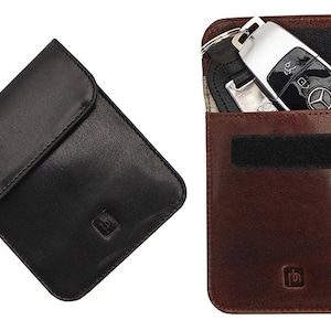 May include: Two leather key holders, one black and one brown. Both have a flap closure and a small logo on the front. The brown key holder has a key with a silver fob inside.