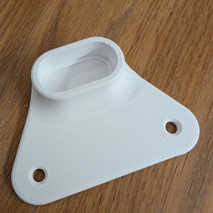 May include: A white, 3D-printed plastic component with an oval-shaped opening and a triangular base. The base features two circular holes and rounded edges. The object is designed with layered textures.