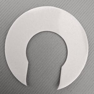 May include: A white, semi-circular object with a keyhole-shaped cutout. The object is made of a smooth, opaque material and is set against a grey, textured background. The shape suggests a possible use as a spacer or a component in a larger assembly.