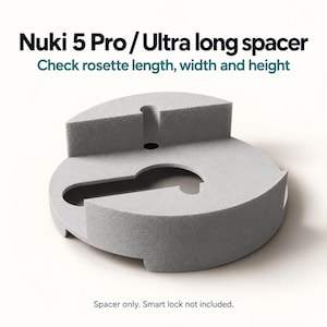 Puede incluir: Un espaciador Nuki 5 Pro / Ultra long de color gris claro con una base circular y un recorte central en forma de cerradura. El texto dice: Nuki 5 Pro / Ultra long spacer, Check rosette length, width and height, Spacer only.