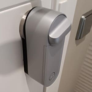 Puede incluir: Una cerradura de puerta plateada con un botón redondo en el lateral.