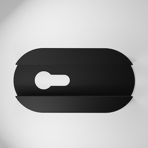 May include: A black, oval wall shelf with a keyhole-shaped opening. The shelf has a minimalist design and is mounted on a white wall. The shelf is approximately 20 cm long.