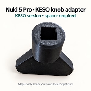 Puede incluir: Un adaptador de pomo Nuki 5 Pro KESO negro con una abertura central cuadrada. El texto dice: Nuki 5 Pro KESO knob adapter, KESO version spacer required, y Adapter only. Check your smart-lock compatibility. El componente tiene un acabado texturizado.