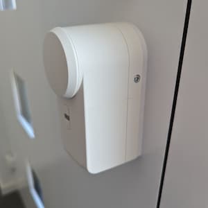 May include: A white door lock with a round knob and a small button on the side. The lock is mounted on a white door.