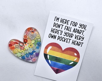 May include: A rainbow heart-shaped resin keychain with colorful embellishments and the text "I'm here for you, don't fall apart, here's your very own pocket heart".