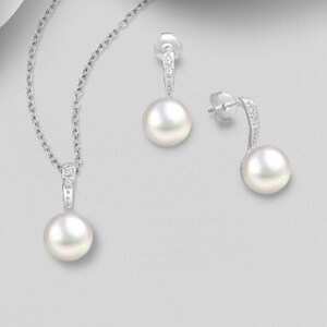 May include: A pearl necklace and earrings set with a silver chain and small diamond accents. The pearls are white and round.