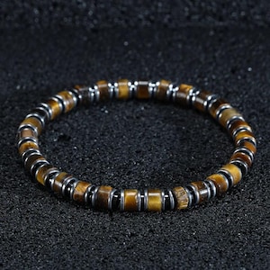 May include: A brown and gold beaded bracelet with silver accents. The bracelet is made of tiger's eye stones and metal beads.