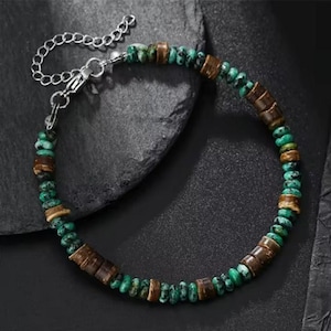 Peut inclure: Un bracelet de perles composé de perles turquoise et marron. Il est doté d'une chaîne et d'un fermoir argentés. Les perles sont disposées en cercle, créant un accessoire unique et élégant.
