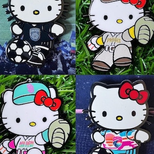Puede incluir: Cuatro pines de esmalte con el personaje de Hello Kitty con uniformes deportivos. Un pin muestra a Hello Kitty con un balón de fútbol, otro con un guante de béisbol y dos con gorras de béisbol. Cada pin tiene un lazo rojo.