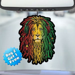 May include: A car air freshener featuring a lion with dreadlocks and headphones. The lion is depicted in red, yellow, and green colors, reminiscent of the Rastafarian flag. The air freshener has a "Buy 2 Get 1 Free" label.