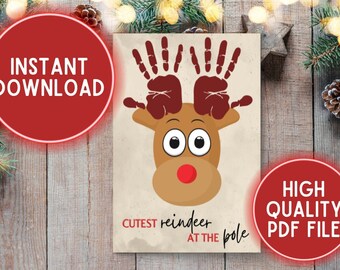 May include: A Christmas-themed print featuring a reindeer design made from handprints. The reindeer has large eyes, a red nose, and handprint antlers. Text on the print reads "Cutest reindeer at the pole". The print is on a rustic wooden background.