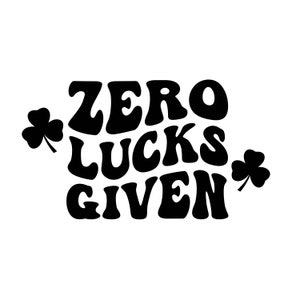 Puede incluir: Diseño gráfico en blanco y negro con el texto "ZERO LUCKS GIVEN" en una fuente retro. Dos símbolos de trébol están a cada lado del texto.