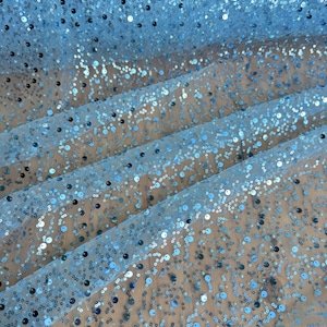 May include: Light blue fabric with scattered sequins. The sequins are small and round, and they are evenly distributed across the fabric.
