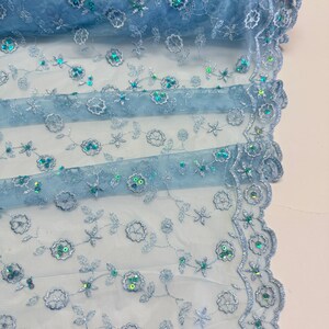 Peut inclure: Tissu brod&eacute; bleu clair avec des d&eacute;tails floraux et des paillettes. Le tissu a un bord festonn&eacute; et le texte "BABY BLUE" est visible. Le texte "LIMITED STOCK Will Not Be Restocked" est &eacute;galement visible.