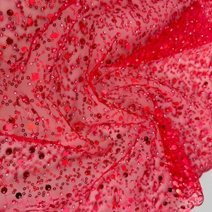 May include: Red sequined fabric with a mesh backing. The sequins are small and evenly distributed across the fabric.