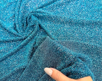 May include: A close-up of teal blue sparkly fabric with a shimmery finish. The fabric is soft and has a subtle texture.