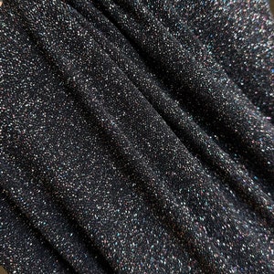 Pode incluir: Close-up de tecido preto com glitter iridescente. O tecido tem uma apar&ecirc;ncia texturizada e tecida.