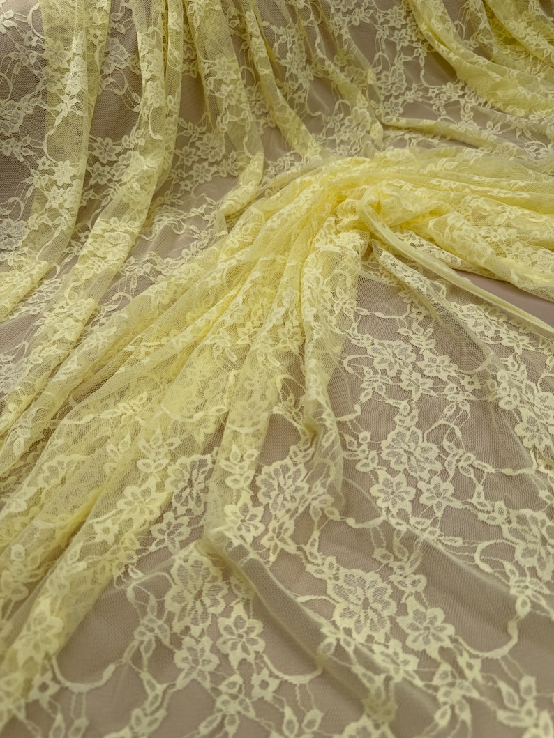 K&ouml;nnte beinhalten: Hellgelber floraler Spitzenstoff. Die zarte Spitze weist ein sich wiederholendes Muster aus Blumen und Bl&auml;ttern auf. Der Stoff ist drapiert und zeigt die komplizierten Details und die Textur der Spitze. Ideal f&uuml;r N&auml;hprojekte, Kleidung oder Heimdekoration.