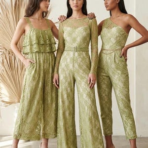 Three women wearing green lace jumpsuits. The jumpsuits have different styles: one with a ruffled top, one with long sleeves and a belt, and one with a one-shoulder design. They are standing in front of a neutral background.
