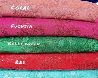 May include: A stack of colorful fabric rolls in shades of royal blue, coral, fuchsia, kelly green, red, tiffany, and pink. Each roll features a floral pattern and the color name in white text.