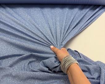 Könnte beinhalten: Eine Rolle hellblauen Stoffes mit einem dezenten Glitzereffekt. Der Stoff wird hochgehalten, wodurch seine Textur und sein Fall sichtbar werden. Der Stoff wirkt weich und eignet sich für Kleidung oder Dekorationsprojekte.