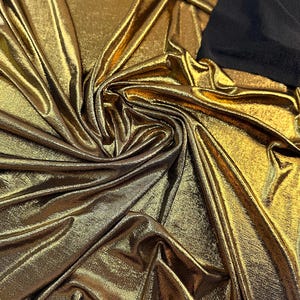 Tecido metálico dourado elástico em 4 direções, vendido por metro. Tecido brilhante e luxuoso, com elastano holográfico para decoração de vestidos de noiva e roupas de dança. Gramatura: 250 g/m².