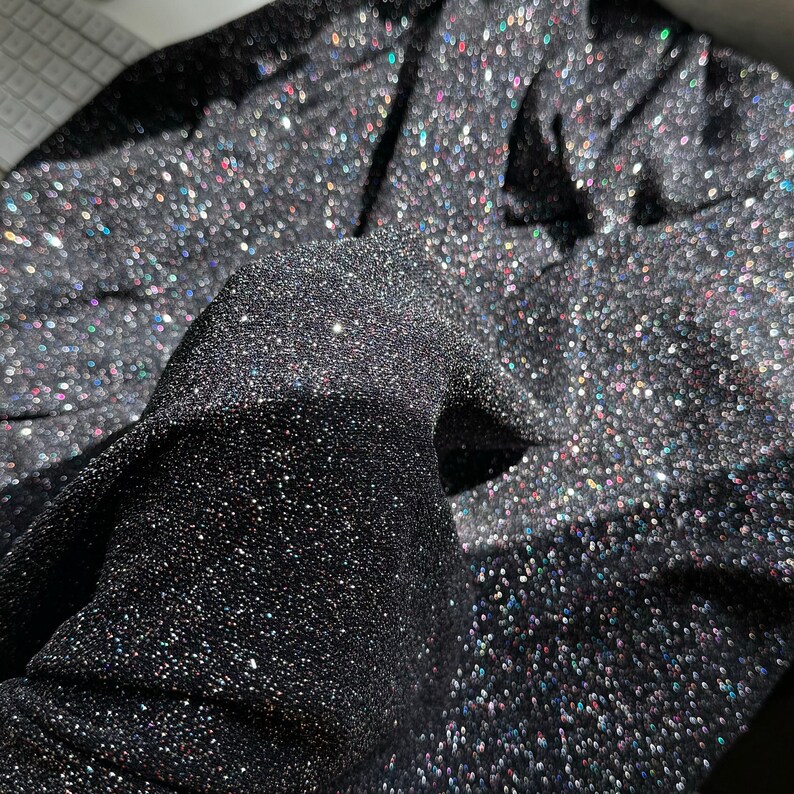 Pode incluir: Tecido preto com glitter iridescente. O tecido &eacute; texturizado e tem um brilho sutil.