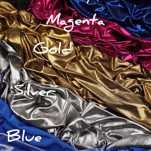 May include: A collection of metallic fabric swatches in various colours including royal blue, magenta, gold, silver, and blue. Each section of fabric features a shiny, reflective surface with draped folds and handwritten labels identifying each colour.