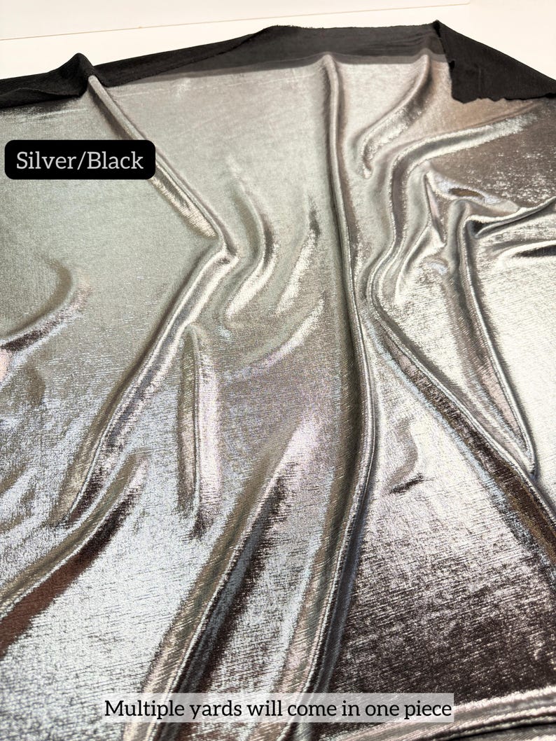 May include: A piece of fabric with a metallic silver finish on a black base, featuring a draped texture. A black label in the upper left corner reads Silver/Black, and text at the bottom states Multiple yards will come in one piece.