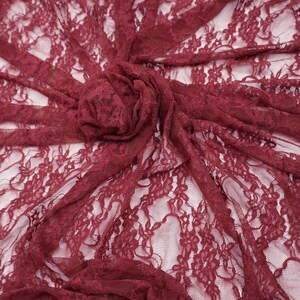 K&ouml;nnte beinhalten: Bordeauxfarbener Spitzenstoff mit floralem Muster. Das zarte Material ist drapiert und gerafft, wodurch ein strukturierter Effekt entsteht. Der Stoff ist halbtransparent und gibt den Hintergrund frei. Ideal f&uuml;r Kleidung und Bastelprojekte.