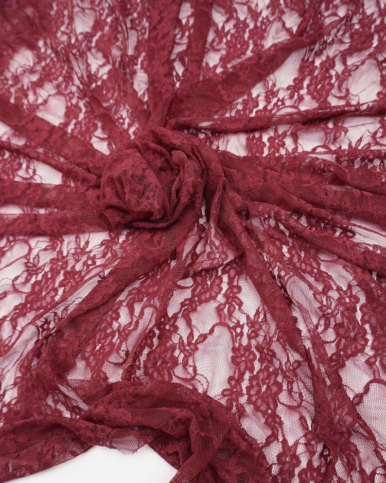 K&ouml;nnte beinhalten: Bordeauxfarbener Spitzenstoff mit floralem Muster. Das zarte Material ist drapiert und gerafft, wodurch ein strukturierter Effekt entsteht. Der Stoff ist halbtransparent und gibt den Hintergrund frei. Ideal f&uuml;r Kleidung und Bastelprojekte.