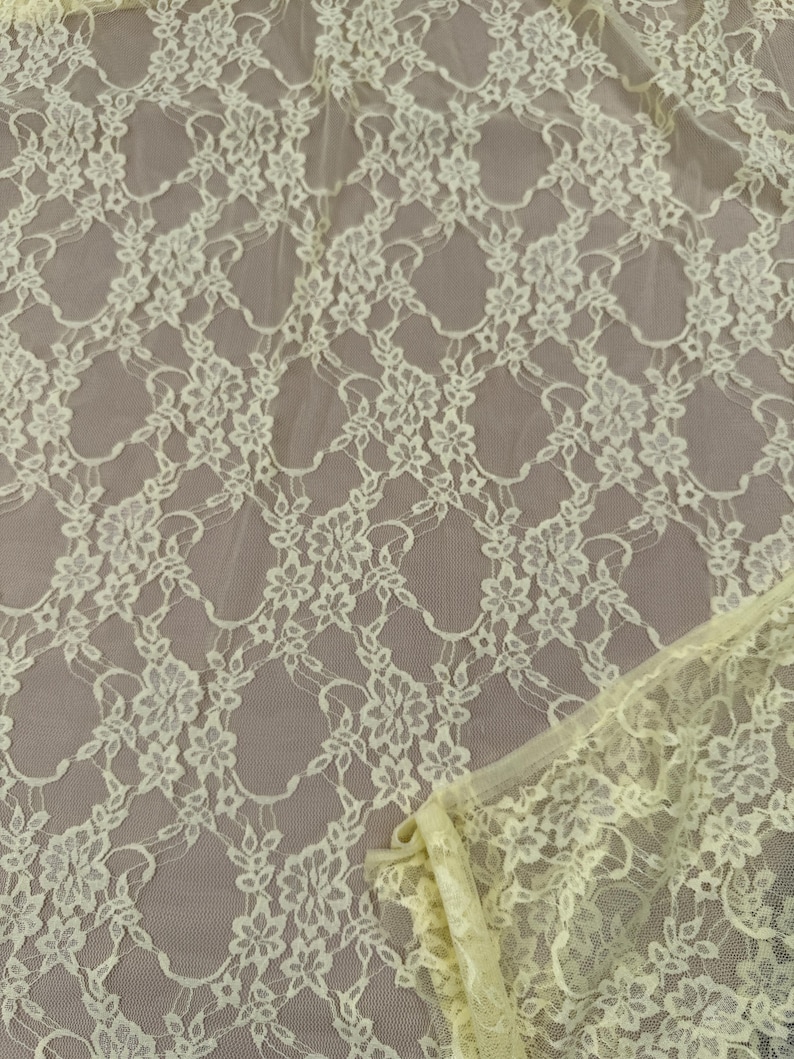 K&ouml;nnte beinhalten: Nahaufnahme eines hellgelben Spitzenstoffs. Die Spitze weist ein Blumenmuster mit zarten, miteinander verbundenen Designs auf. Der Stoff hat ein weiches, luftiges Aussehen mit einer leicht transparenten Qualit&auml;t. Die Kanten des Stoffes sind sichtbar und zeigen die Textur und die Details.