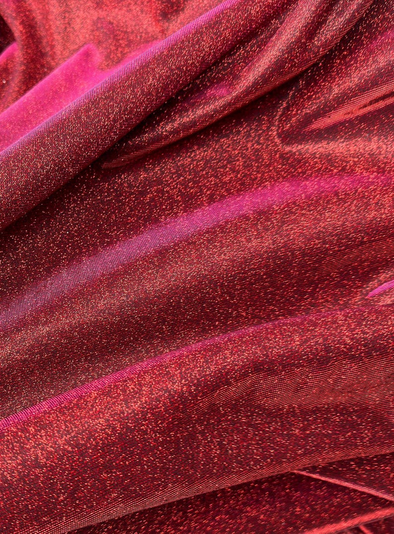 May include: Red sparkly fabric with a subtle pink sheen. The fabric has a fine, woven texture and a shimmery finish.