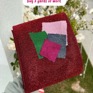 May include: Red, pink, green, and dark gray fabric swatches on a red sparkly fabric. The text "Free samples when you buy 3 yards or more" is written in white on a pink background.