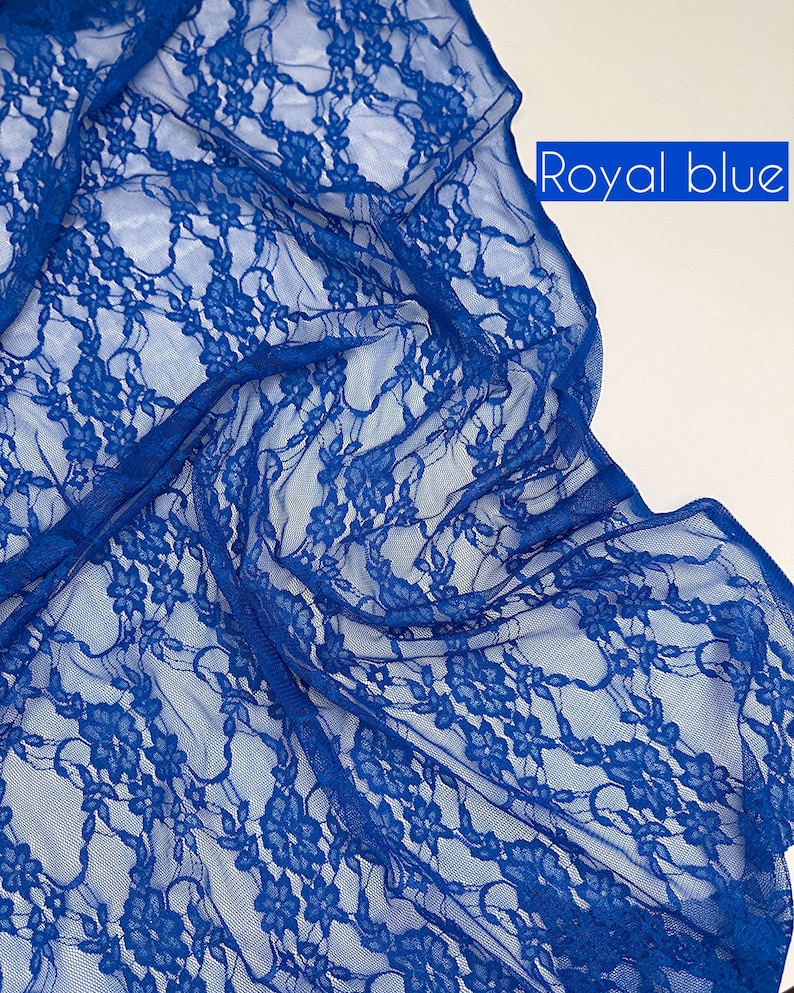 May include: Royal blue lace fabric with a floral pattern. The delicate, sheer material is draped, showcasing the intricate design. The text "Royal blue" is displayed in a white rectangle in the upper right corner.