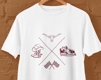 Puede incluir: Camiseta blanca con un diseño gráfico marrón que representa un sombrero de vaquero, botas, una cabeza de toro, un coche de carreras y banderas a cuadros. El gráfico está centrado en la camiseta y está rodeado de un fondo blanco.