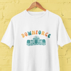 May include: White t-shirt featuring a green and orange graphic of a racing car and the text "DOWNFORCE" in a retro font.
