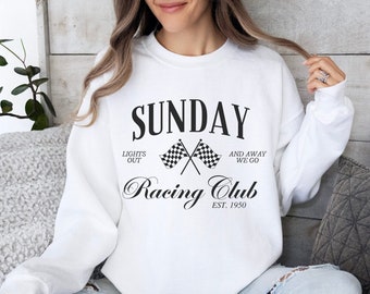 Peut inclure: Sweat-shirt blanc avec l'inscription "SUNDAY Racing Club" en noir. Le motif comprend des drapeaux à damiers croisés et les phrases "Lights Out" et "And Away We Go". Style décontracté.