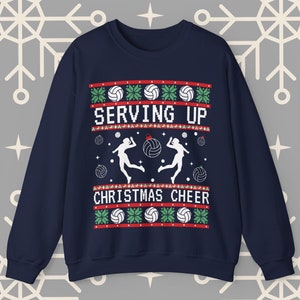 Op de afbeelding: Donkerblauwe trui met een kerstthema met twee volleyballers en de tekst "SERVING UP CHRISTMAS CHEER".