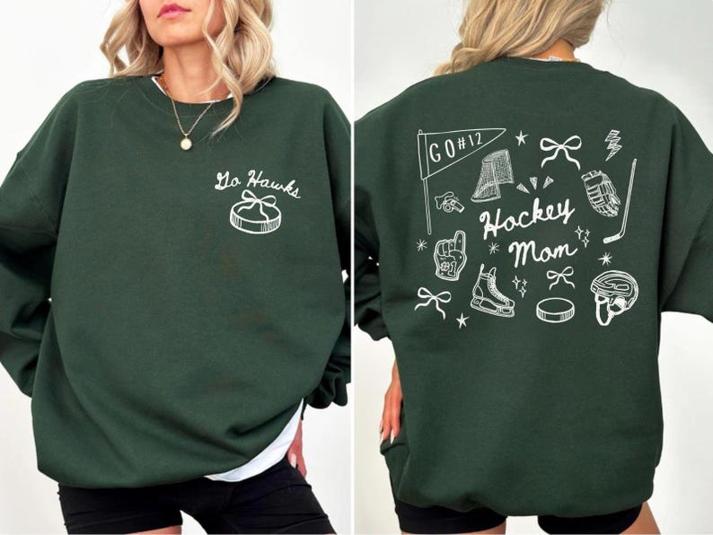 Woman wearing a crewneck sweatshirt with “Hockey Mom” doodle graphic on the back and personalized team name "Go Hawks" and player number "12" on the front; casual hockey game day outfit for moms.