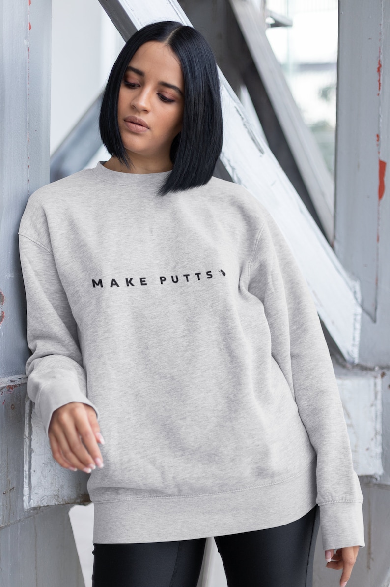 May include: A gray sweatshirt with the text "MAKE PUTTS" printed on the front.