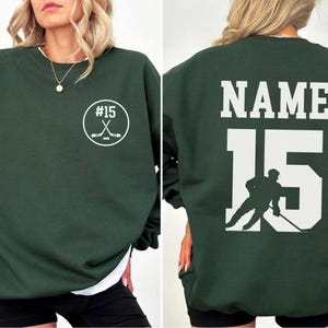 Custom hockey sweatshirt featuring a personalized hockey player name and number design on the back as well as jersey number on the front design.  Also, choose from a variety of hockey player silhouettes to further customize this hockey sweater