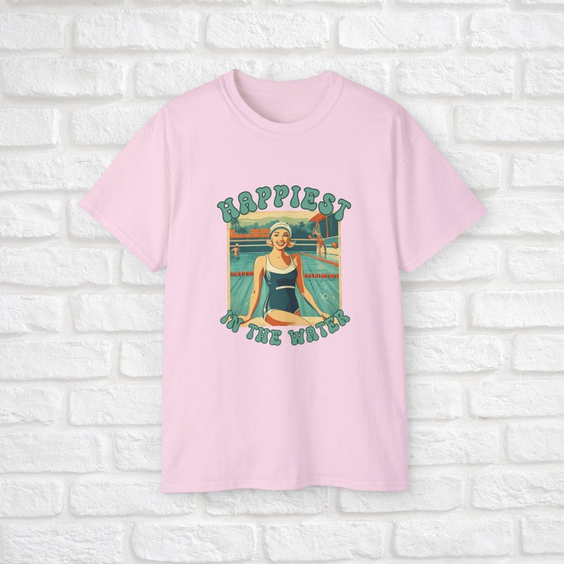May include: Pink t-shirt with a retro graphic of a woman in a swimming pool. The graphic says "Happiest in the water".