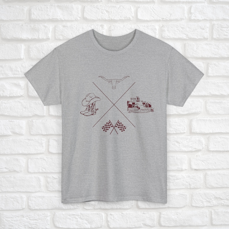 K&ouml;nnte beinhalten: Ein graues T-Shirt mit einem kastanienbraunen Design, das einen Cowboyhut, Stiefel, einen Longhorn-Stier, ein Rennwagen und karierte Flaggen zeigt.