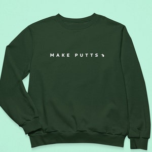 May include: A dark green sweatshirt with the text "MAKE PUTTS" in white on the front.